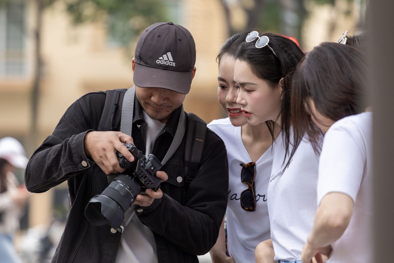 The Art of Drawing Readers In: Your attractive post title goes here A group of young adults in Hanoi reviewing photos on a camera screen. Outdoor urban setting.